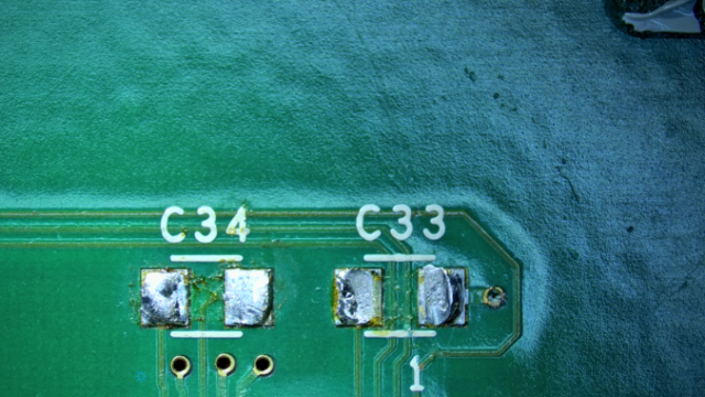 Picture of C34 and C33 on a PCB where the Caps are ripped of.